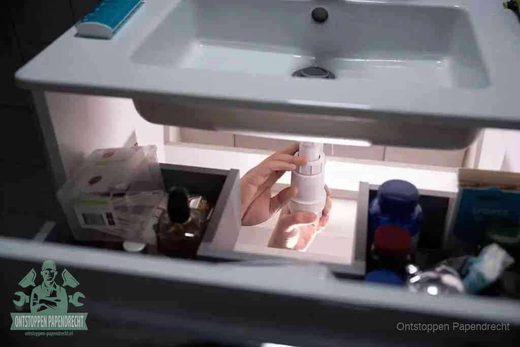 Een pompfles met zeep boven een wastafel, de heet water en afwasmiddel-methode om een vetprop in de afvoer los te maken in Papendrecht