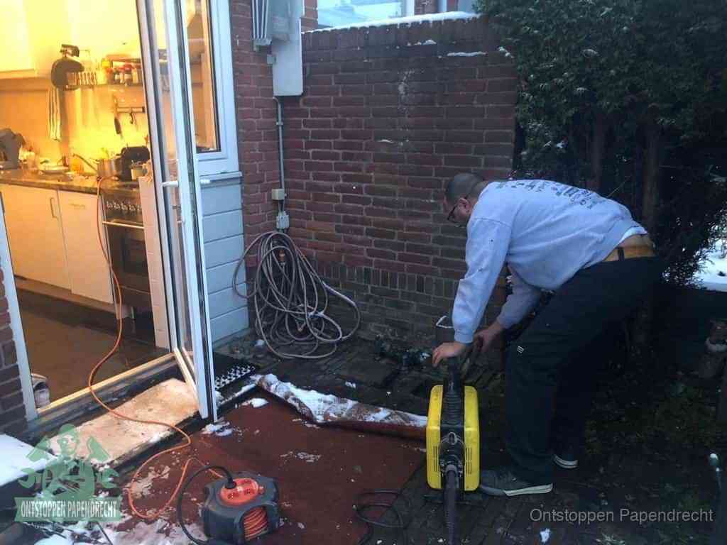 Een monteur werkt buiten bij een open riool-/grondput met een elektrische ontstoppingsmachine om een verborgen afvoerprobleem op te sporen in Papendrecht