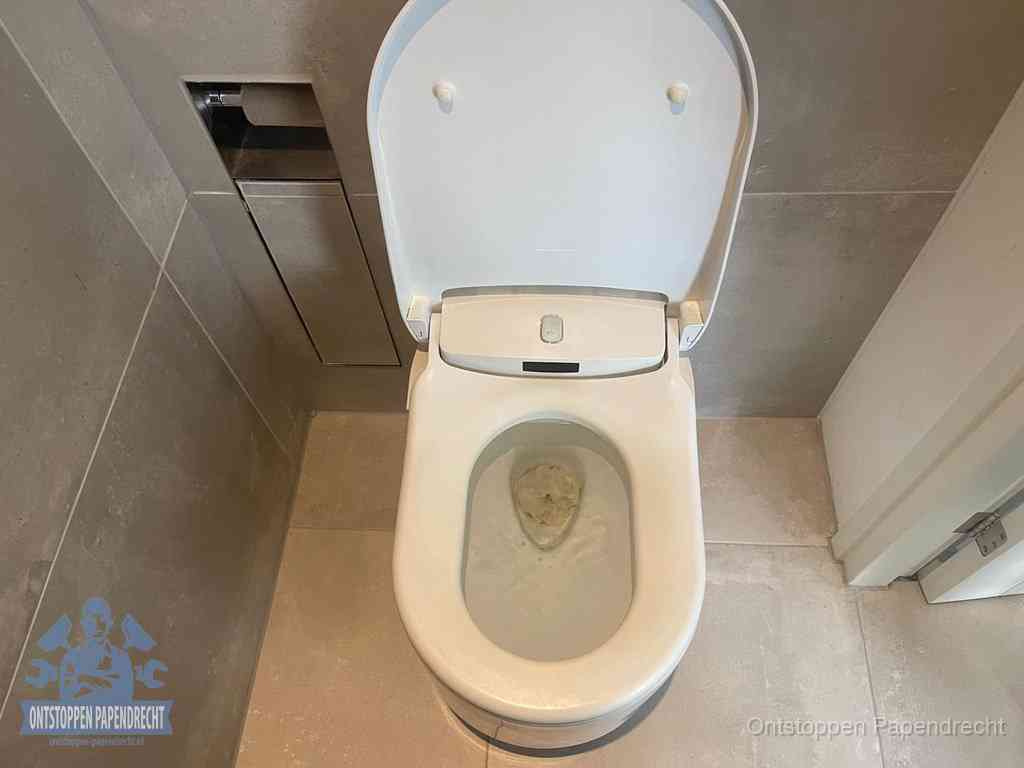 Een wit hangtoilet waarin een prop wc-papier op het water blijft drijven, een duidelijk signaal van een verstopte wc in Papendrecht