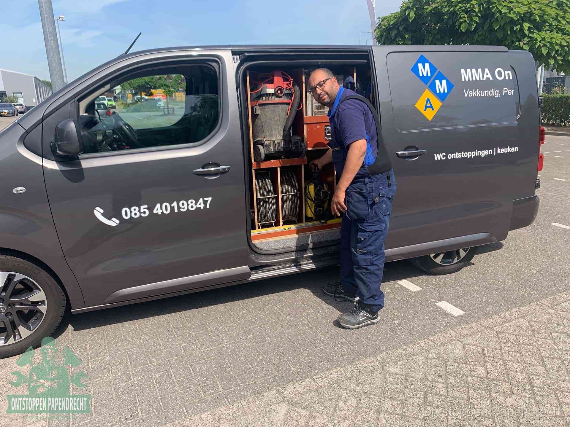 Een monteur bij de open schuifdeur van zijn bedrijfsbus op een parkeerplaats, klaar om de oorzaak van terugkerende afvoerverstoppingen aan te pakken in Papendrecht