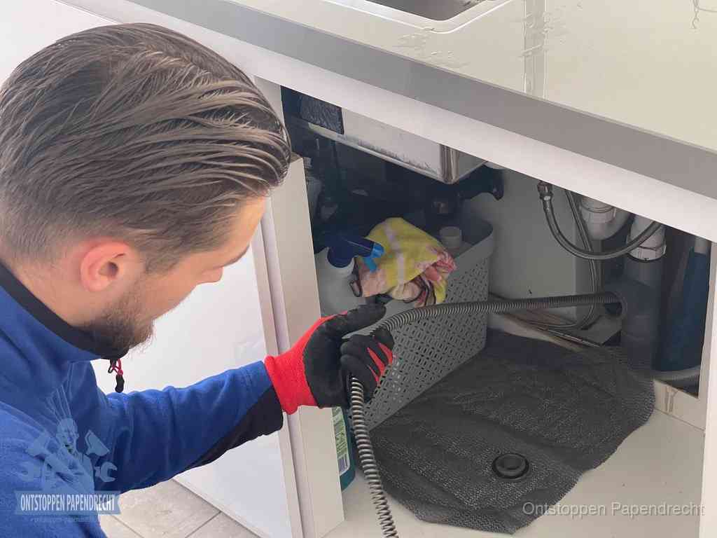 Een monteur voert een flexibele ontstoppingsveer in de afvoer om een verstopping voorbij de bocht van het toilet te bereiken in Papendrecht