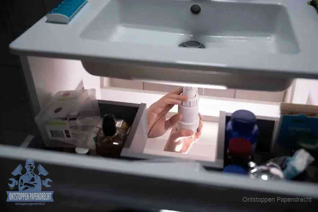 Een pompfles met zeep boven een wastafel in de toiletruimte, de warm water en afwasmiddel-methode om de wc te ontstoppen in Papendrecht