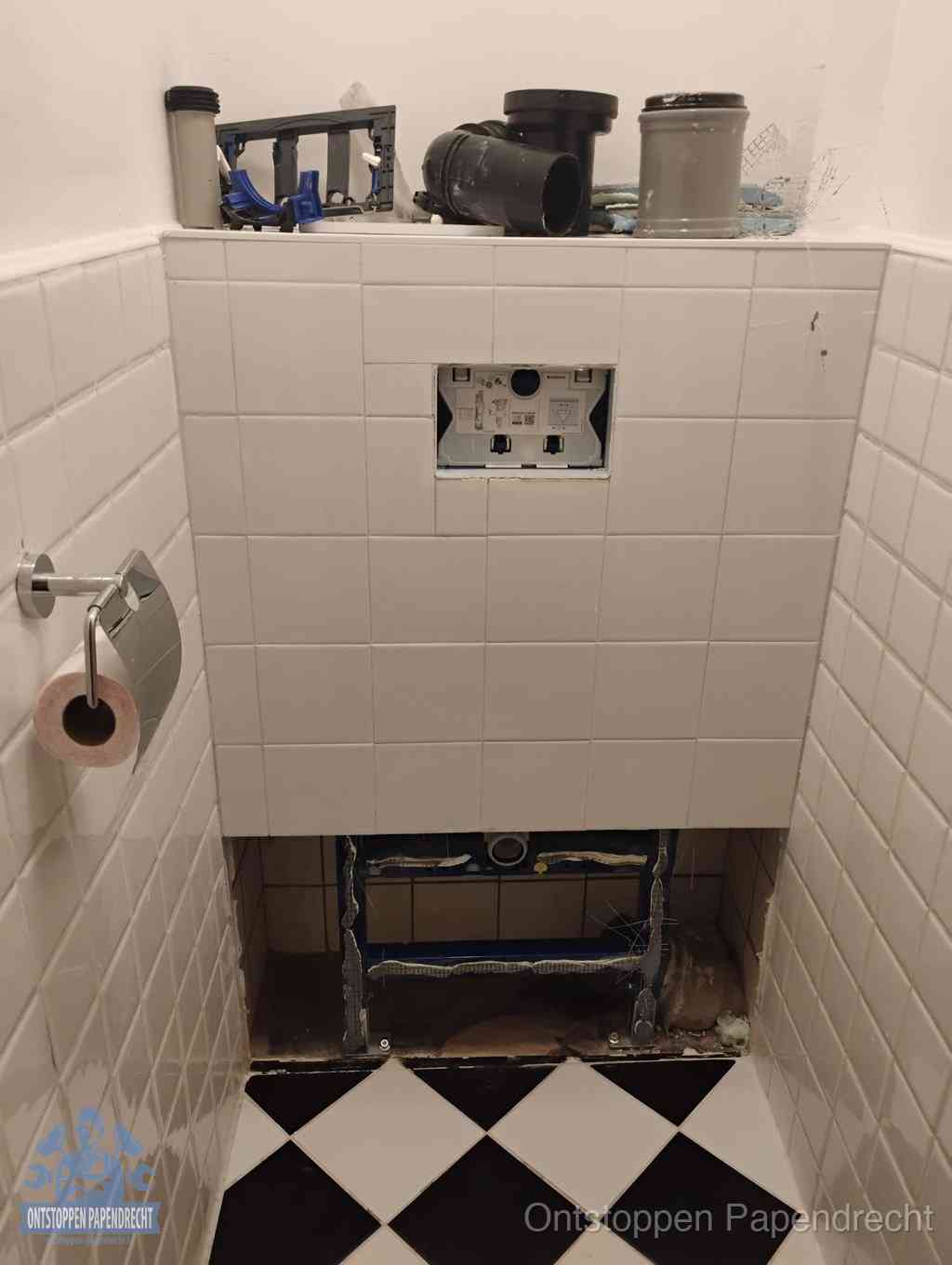 Een toiletruimte waar het hangtoilet en de inbouwreservoir-onderdelen zijn vrijgelegd voor onderhoud, periodiek nazicht voorkomt een wc-verstopping in Papendrecht