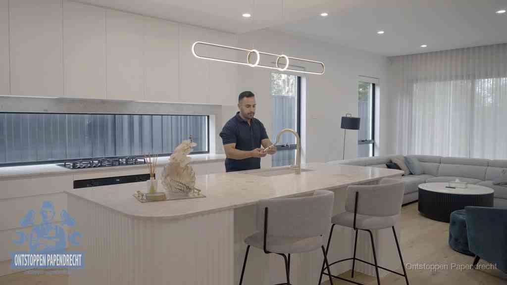 Een bewoner bij de keukenspoelbak die zelf aan de slag gaat met een verstopte gootsteen in Papendrecht